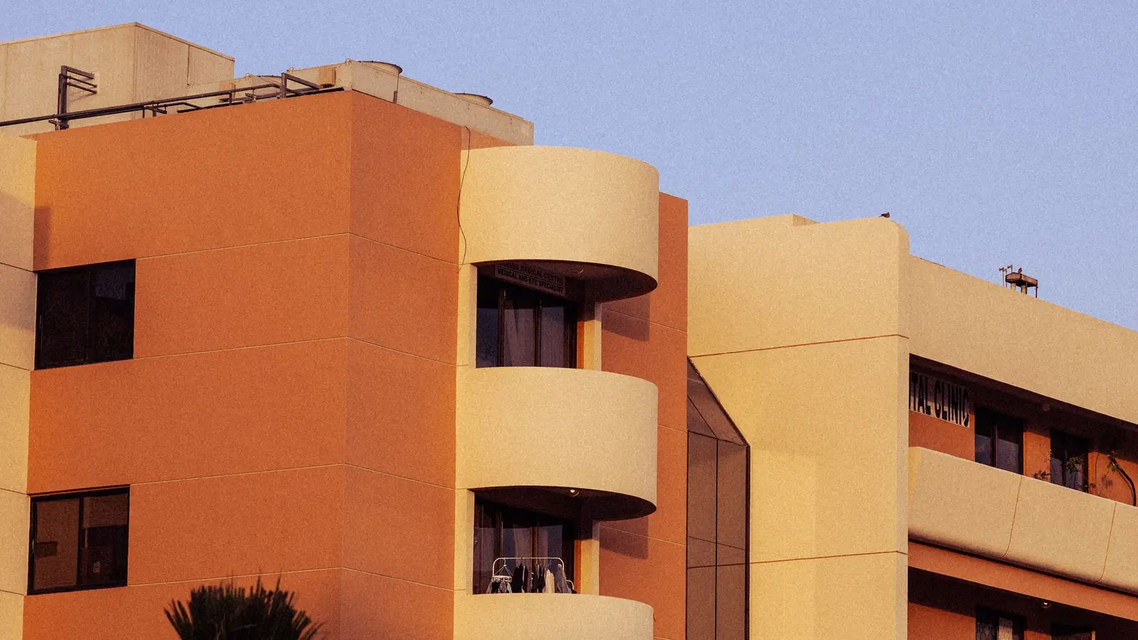 Apartment building with balconies and palm trees at sunset